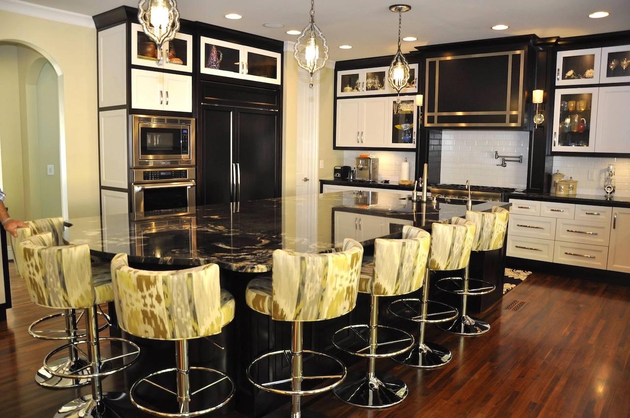 Photo of kitchen with dark granite counters, white cabinets framed by dark painted trim and hardwood floor. Granite island seats 8 with a built in sink