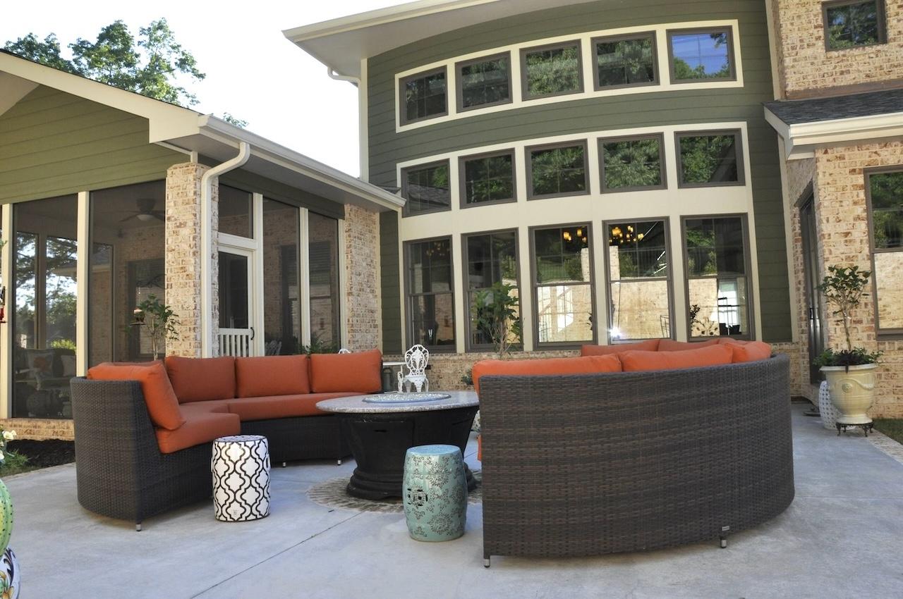 Photo of patio outdoor living space off of a screened porch and in front of a three story windowed wall of the home