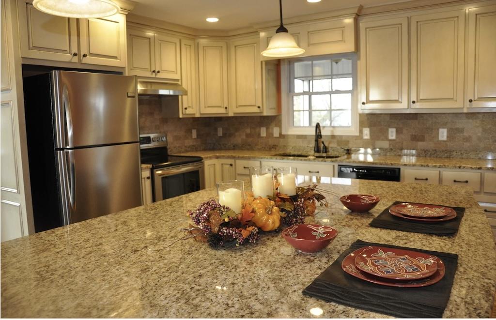 Photo of kitchen with granite countertops, built in fridge and white cabinets